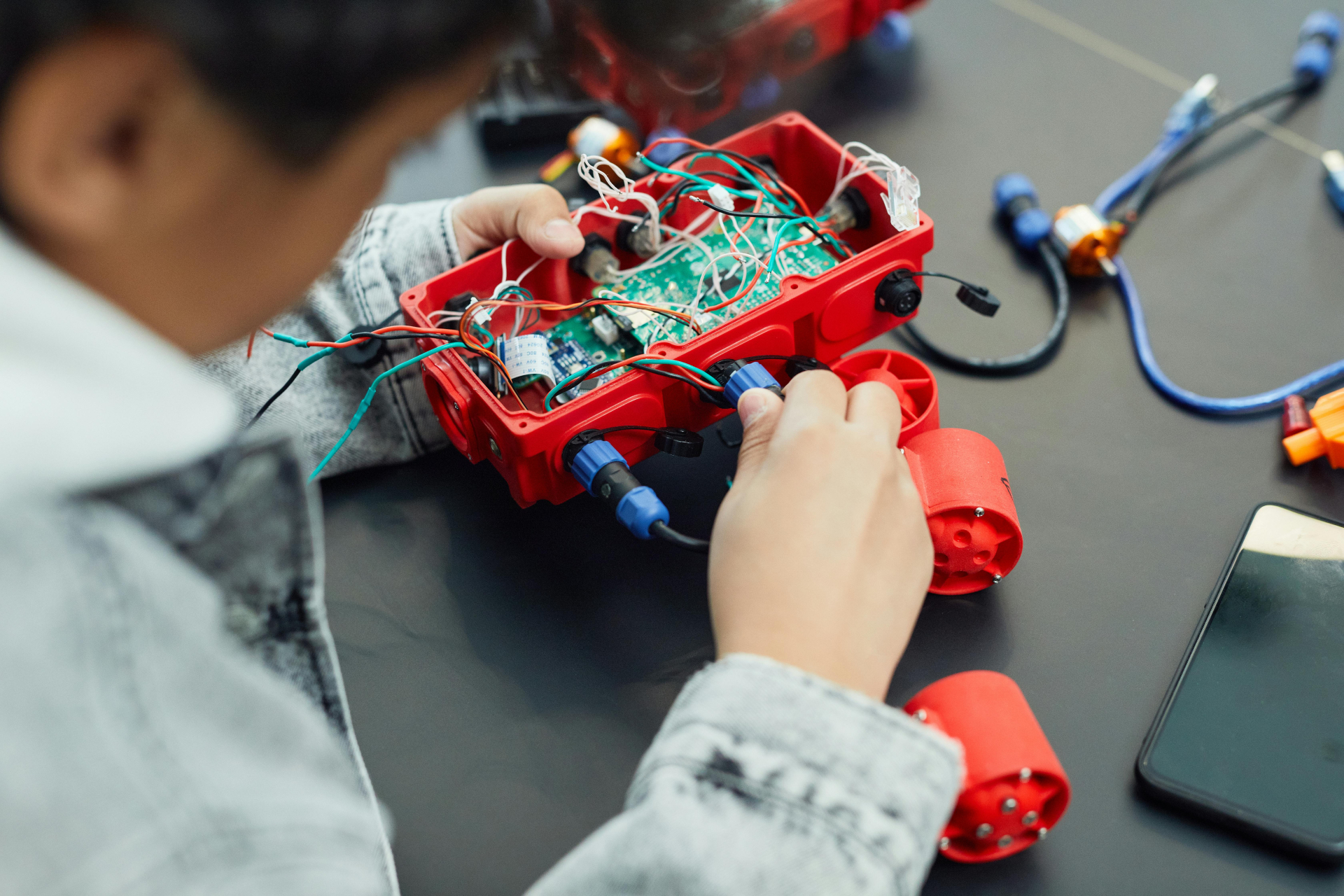 A imagem mostra um menino montando um carrinho em uma aula de robótica