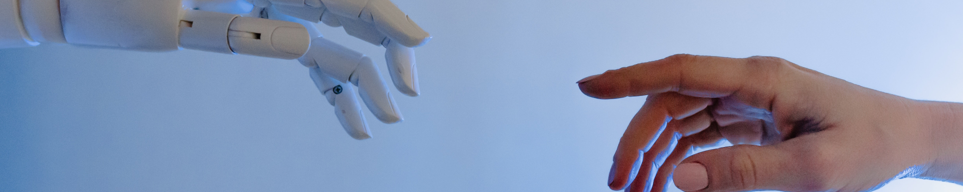 Duas mãos estão quase se tocando. Uma delas é de um robô.