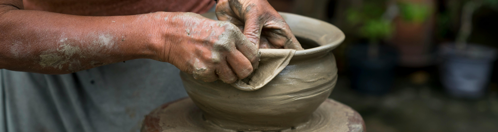 Uma pessoa molda um vaso de barro.