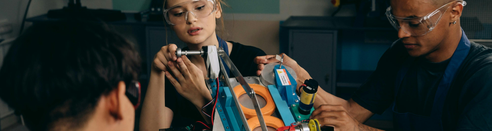 A imagem mostra três pessoas em um projeto de robótica