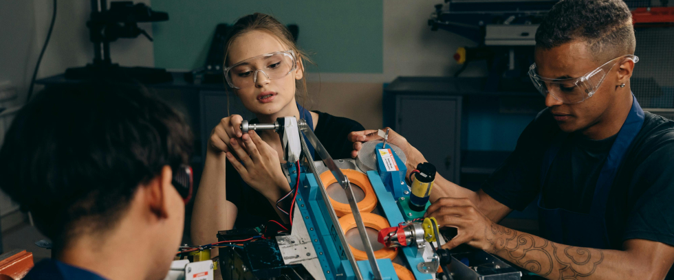 A imagem mostra três pessoas em um projeto de robótica
