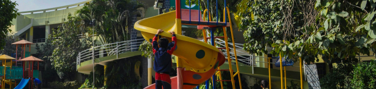 A imagem mostra crianças brincando no parquinho de uma escola