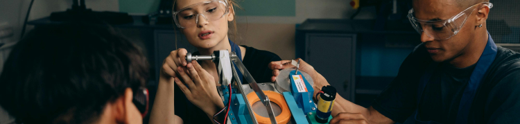 A imagem mostra três pessoas em um projeto de robótica