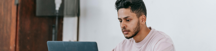 A imagem mostra um jovem rapaz usando um notebook